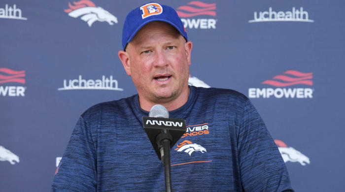 The Broncos coach speaking at a podium.